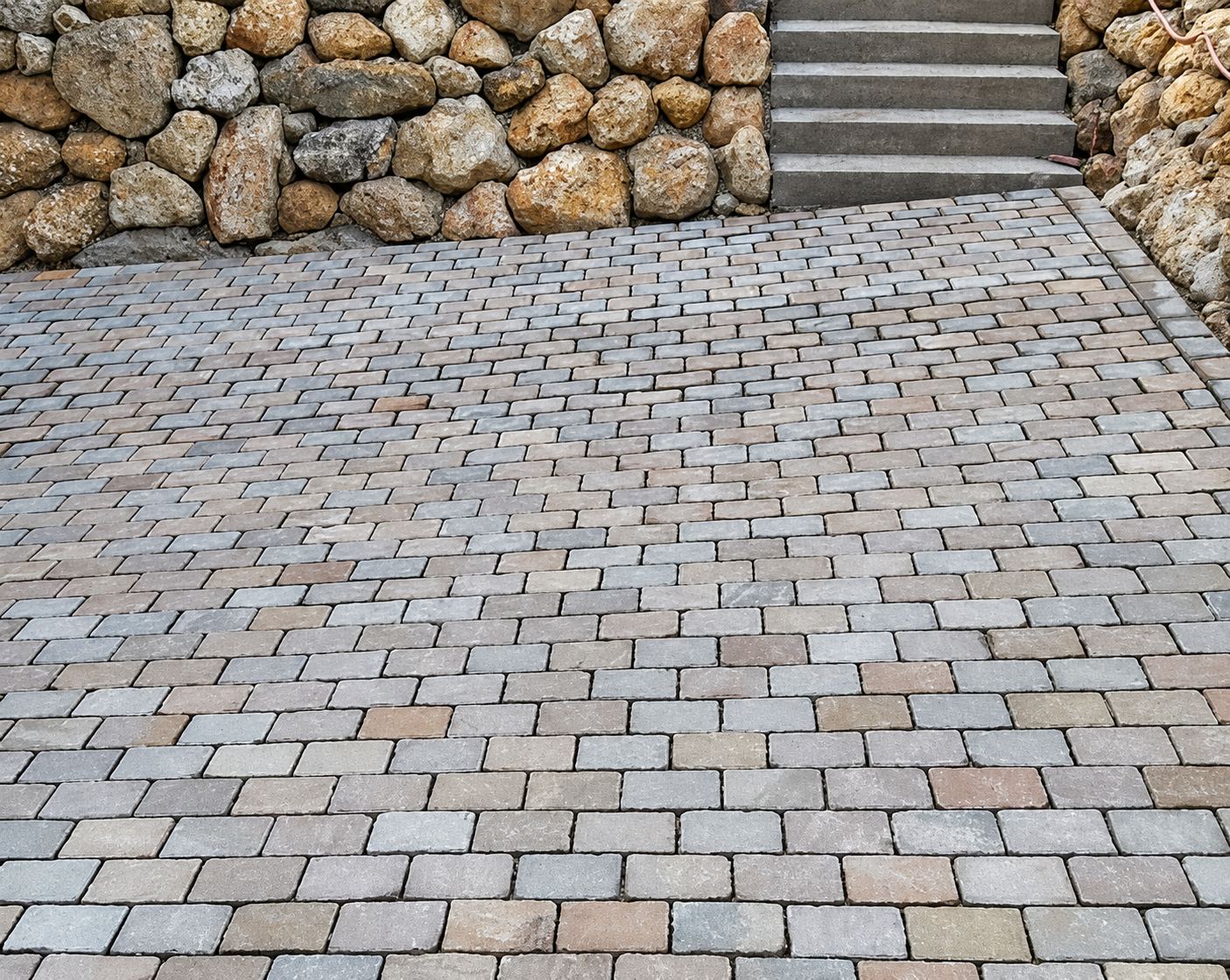 Pavage en pavés de pierre au pied d’un mur en pierres et d’un escalier