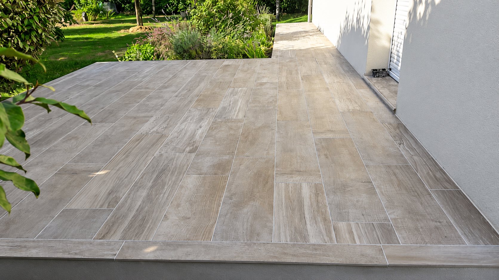 Terrasse carrelée aspect bois le long d’une maison